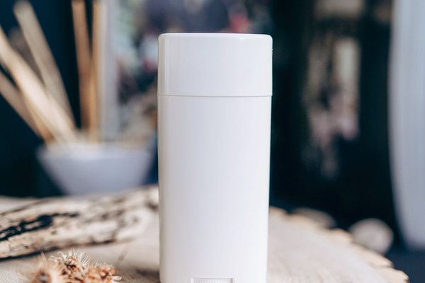 Close-up of a plain white deodorant container resting on a textured wooden surface.
