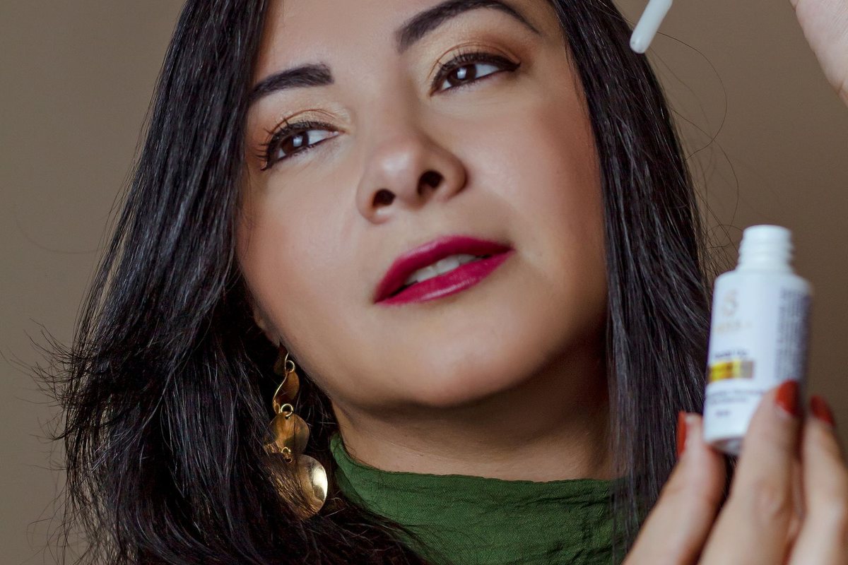 Portrait of a woman using skincare serum with a dropper for facial care.
