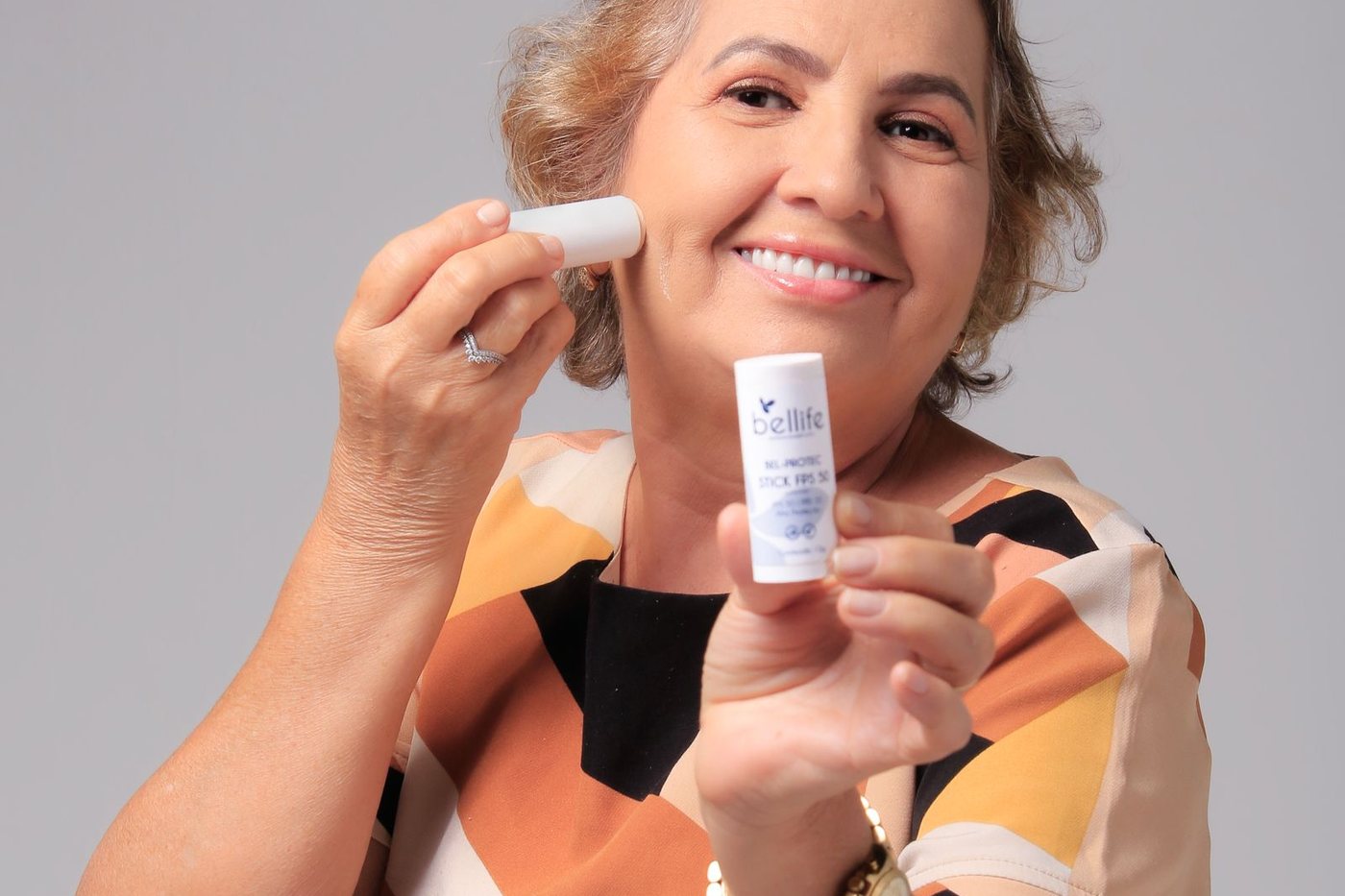Smiling senior woman using skincare product for healthy skin routine.