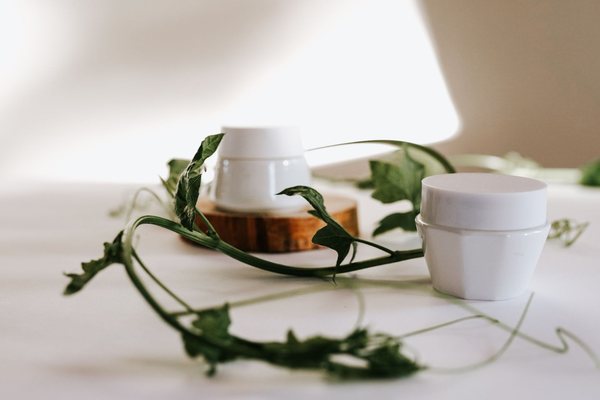 Unlabelled white cream jars with green leaves, the kind of plain everyday moisturisers phenoxyethanol is used to preserve.